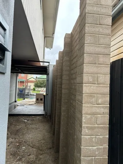 Long grey blockwork boundary wall between buildings