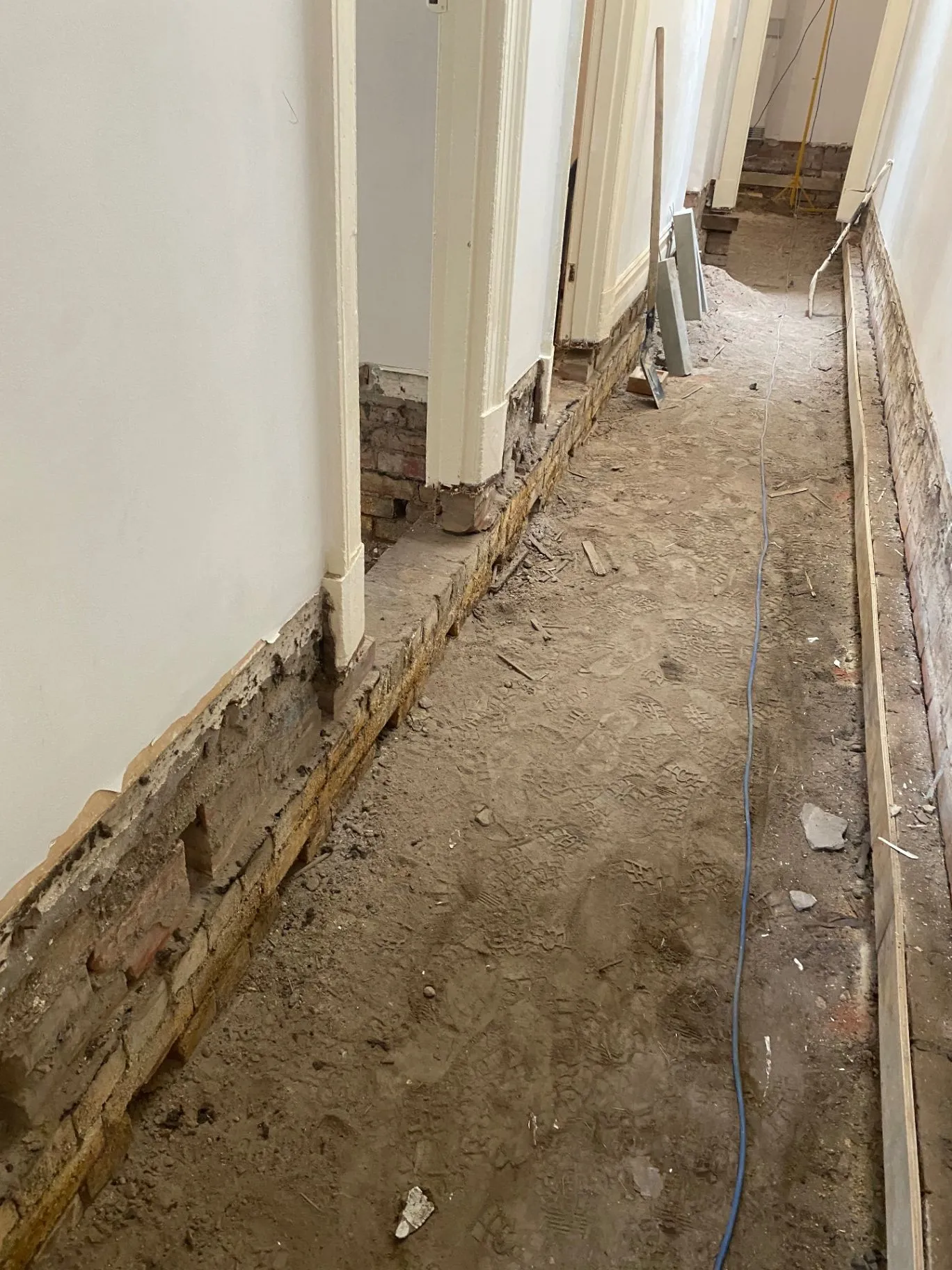 Elsternwick hallway with lower wall structure and brickwork exposed during repair work